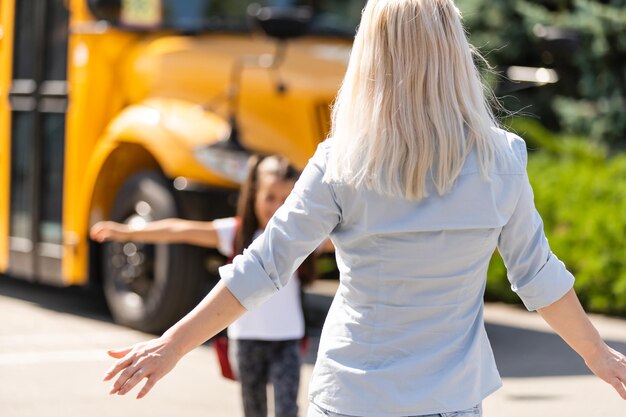 Hermosa niña pequeña con madre cerca de la escuela