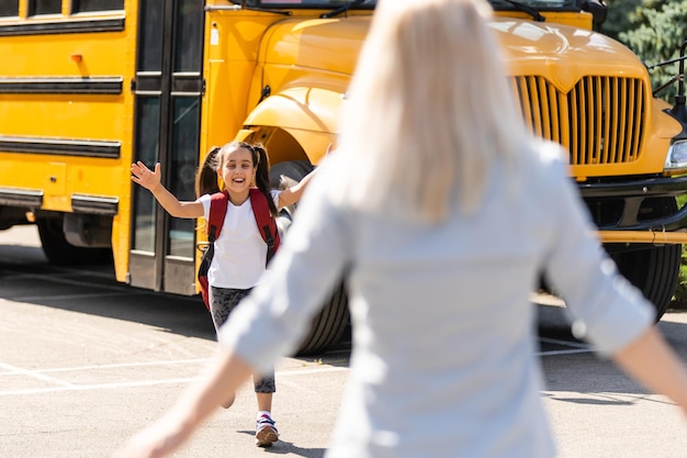 Foto hermosa niña pequeña con madre cerca de la escuela