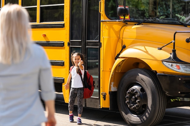 Hermosa niña pequeña con madre cerca de la escuela