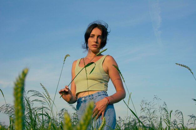 Una hermosa niña posa en un campo de trigo contra un cielo azul.