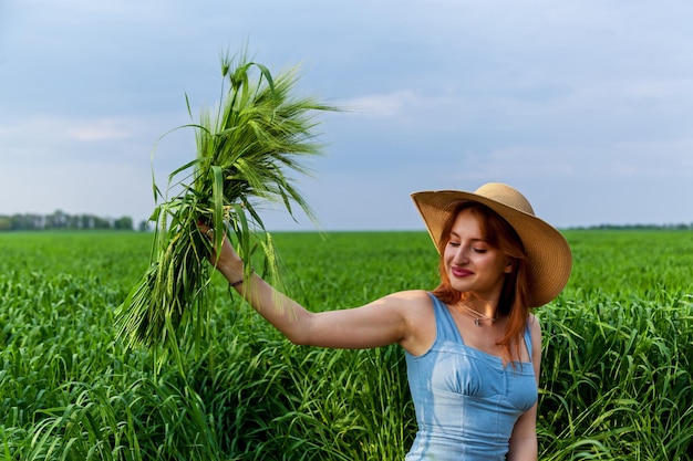 Foto una hermosa niña con un ramo de orejas de trigo verde