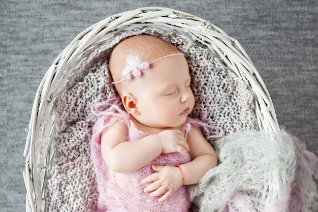 Hermosa niña recién nacida duerme en una canasta de barbas