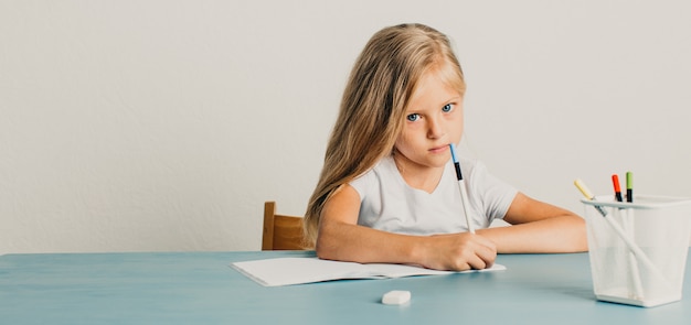 Hermosa niña rubia en una camiseta blanca escribiendo