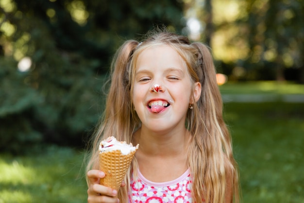 Hermosa niña rubia comiendo helado en el verano en el parque. chica alegre con helado.