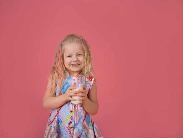 Hermosa niña rubia con leche sobre fondo rosa