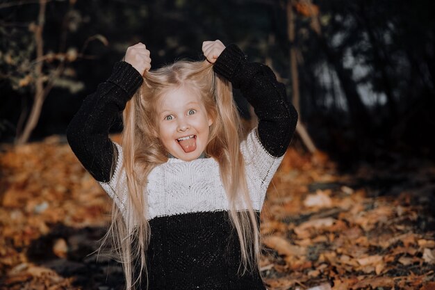 Hermosa niña rubia en el parque en otoño