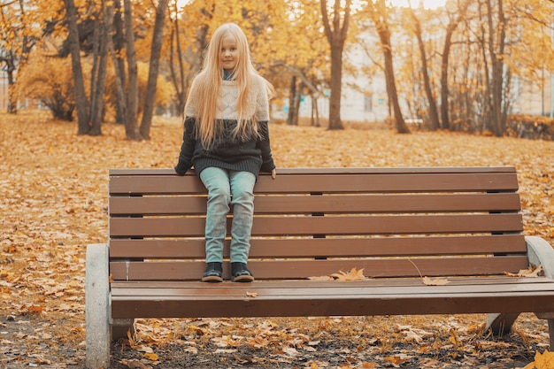 Foto hermosa niña rubia en el parque en otoño