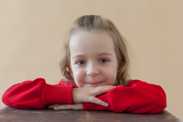 Hermosa niña rubia rizada en traje de deporte rojo. Moda casual con estilo para el concepto de niños