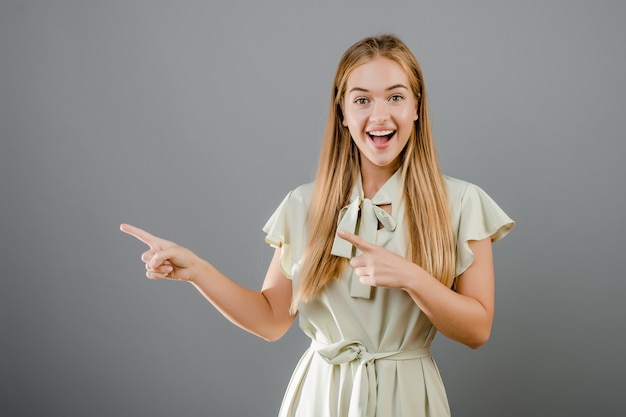 Hermosa niña rubia sonriente señalando copyspace aislado