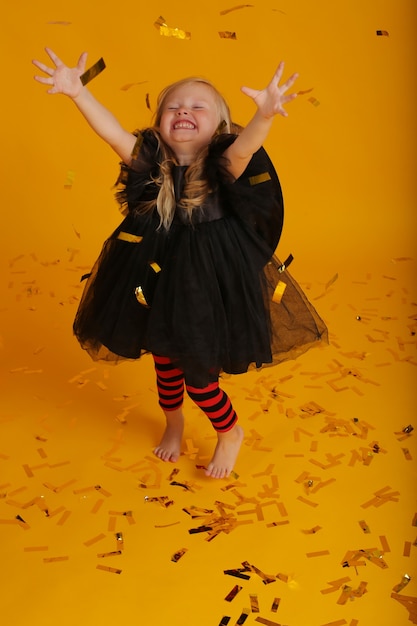 hermosa niña rubia con un vestido negro en leggings negros y rojos un sombrero de bruja halloween