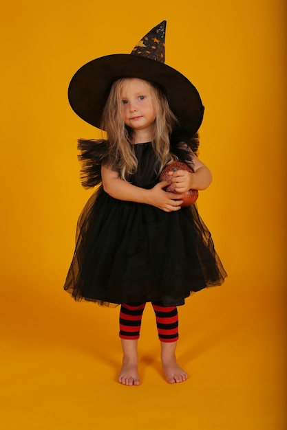 hermosa niña rubia con un vestido negro y un sombrero de bruja halloween
