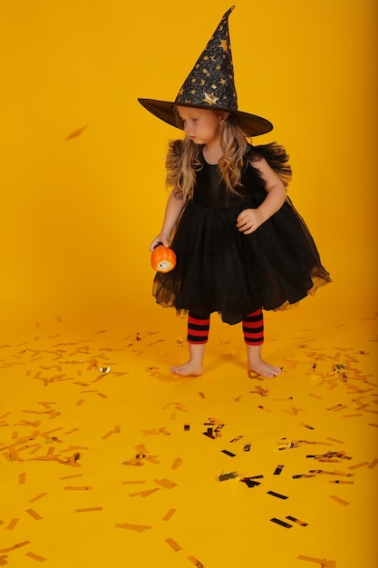 hermosa niña rubia con un vestido negro y un sombrero de bruja halloween