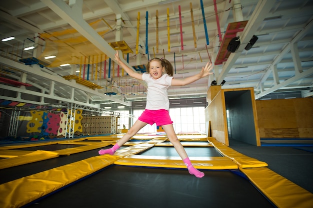 Foto hermosa niña saltando sobre un trampolín en un club de juegos