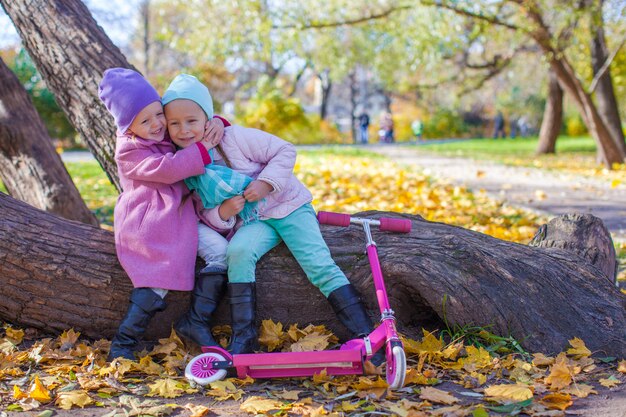 Hermosa niña con scooter en el parque otoño