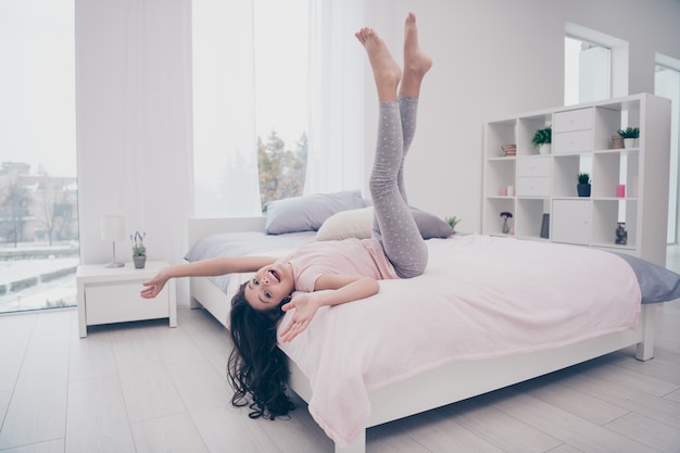 Hermosa niña sentada en su cama en el dormitorio