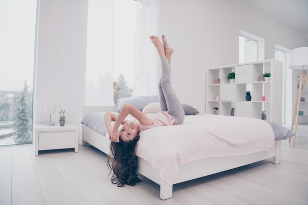 Hermosa niña sentada en su cama en el dormitorio