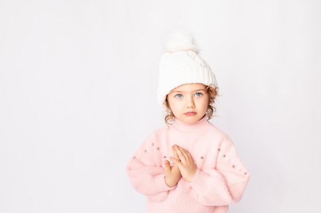 Hermosa niña sobre un fondo blanco aislado en un suéter rosa doblado lindos bolígrafos como si rezara espacio para el texto