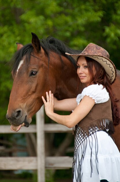 Una hermosa niña con un sombrero de vaquero con un caballo.