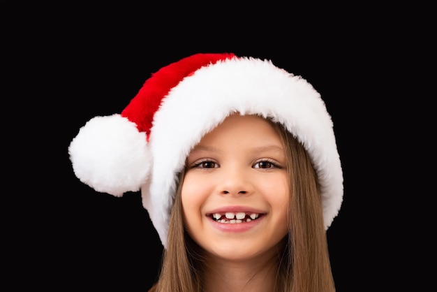 Una hermosa niña sonríe con un sombrero de Navidad.