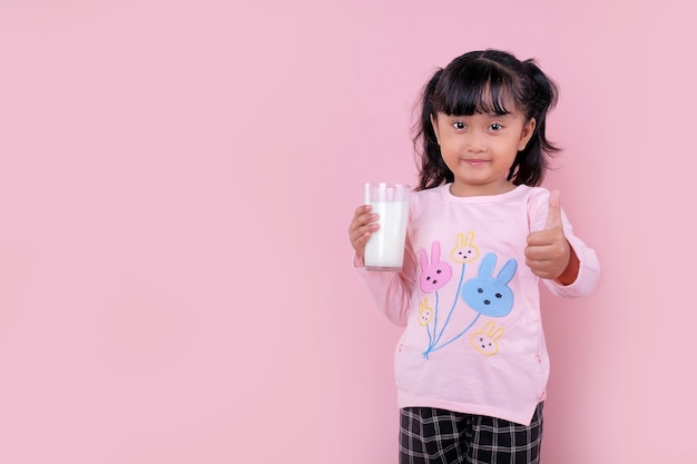 Una hermosa niña sonriendo y sosteniendo un vaso de leche