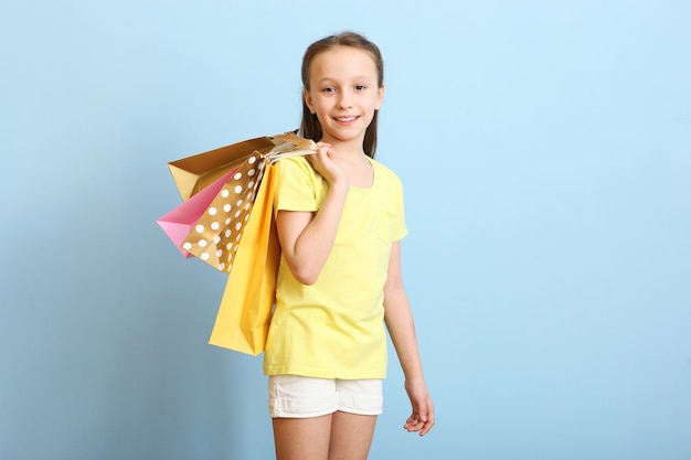 Hermosa niña sonriente con bolsas de compras sobre un fondo de color