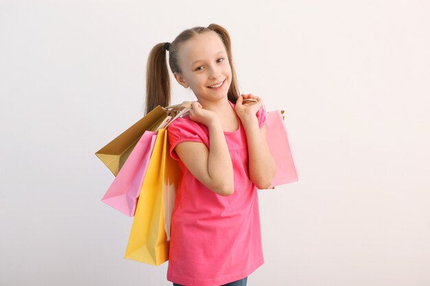 Hermosa niña sonriente con bolsas de compras sobre un fondo de color