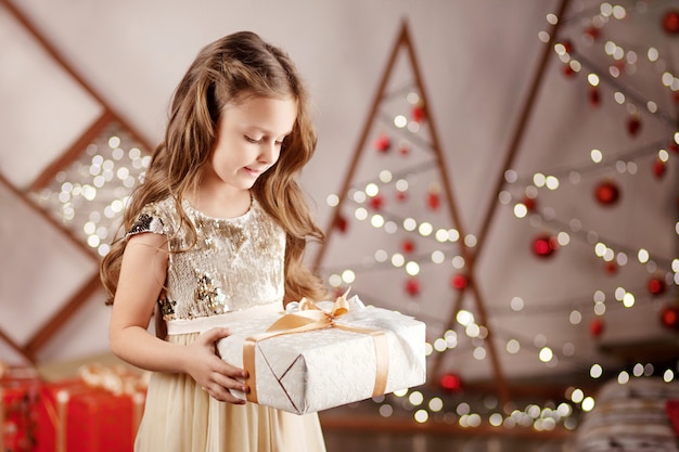 Hermosa niña sonriente con una caja de regalo de Navidad