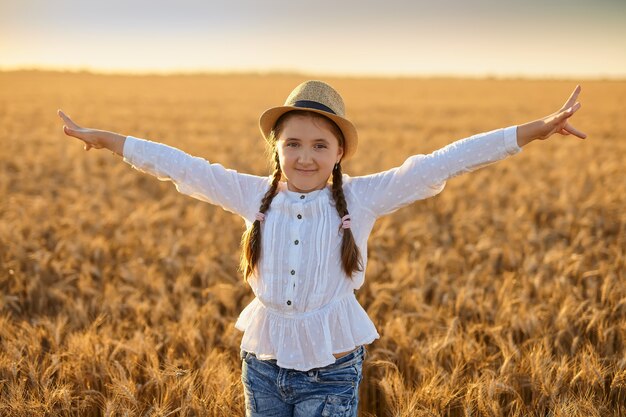 Hermosa niña sonriente en un campo de trigo dorado