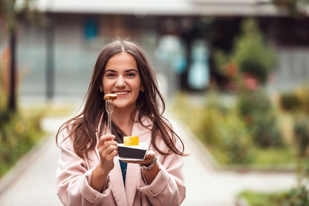 Una hermosa niña sonriente come poffertjes frescos mientras recorre la ciudad Enfoque selectivo