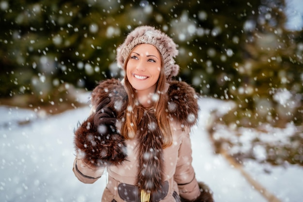 Hermosa niña sonriente dando un paseo mientras está nevando.