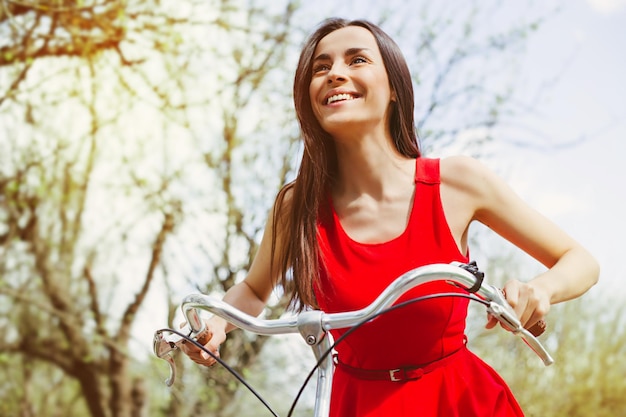 Hermosa niña sonriente está montando la bicicleta en el parque