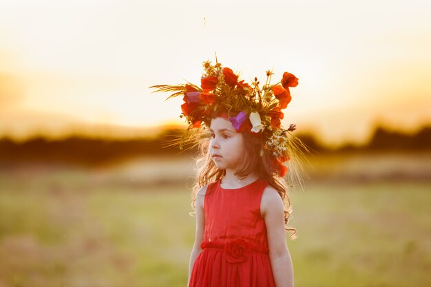 Hermosa niña sonriente con un vestido rojo está girando con una corona en la cabeza