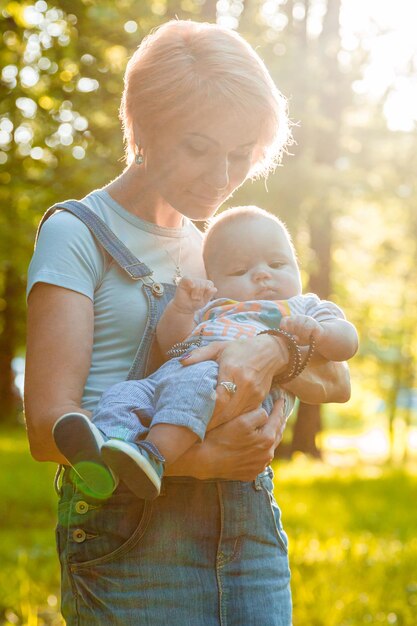 Hermosa niña sosteniendo a un niño en sus brazos en un parque de verano