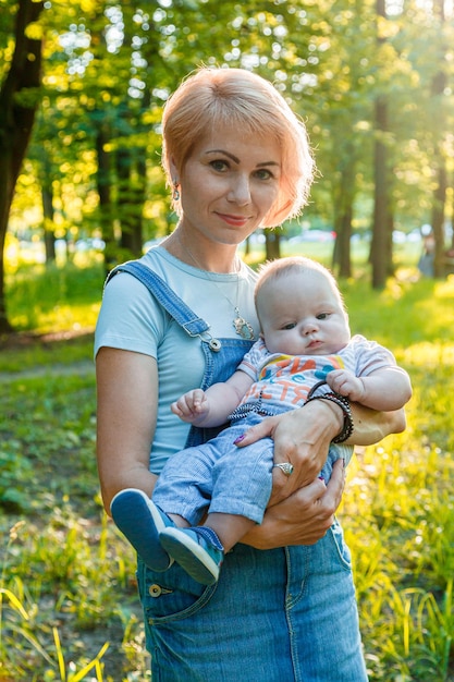 Hermosa niña sosteniendo a un niño en sus brazos en un parque de verano