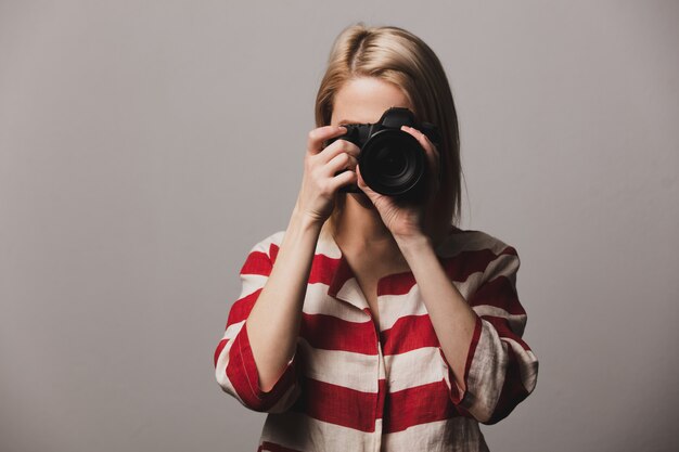 Hermosa niña sostiene la cámara de fotos en las manos