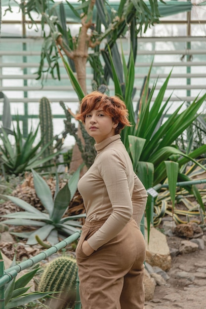 Una hermosa niña de talla grande disfrutando de pie entre las plantas verdes