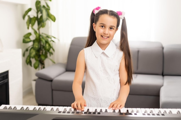 hermosa niña tocando el piano en la sala de luz.