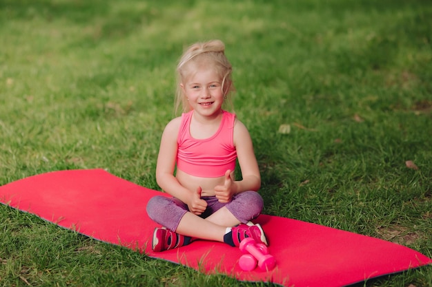 Una hermosa niña ucraniana de 7 años con el pelo blanco como un ángel se dedica al fitness