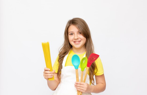 Hermosa niña en uniforme de chef aislado en blanco