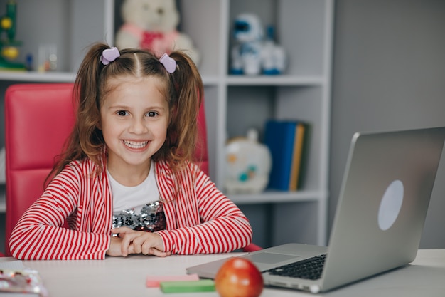 Hermosa niña usando una computadora portátil en casa