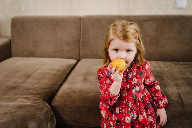 Hermosa niña vestida come limón en casa Retrato de un niño Concepto de vacaciones