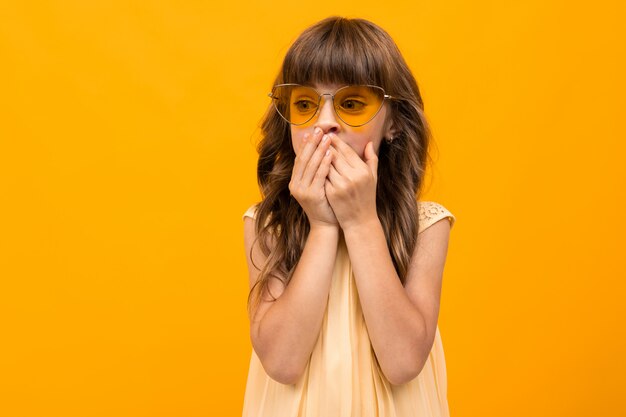 Hermosa niña en vestido aislado en amarillo o naranja