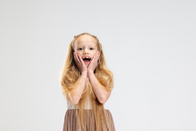 Hermosa niña en vestido elegante moderno posando aislada sobre fondo blanco de estudio Concepto de infancia feliz