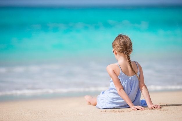 Hermosa niña en vestido en la playa divirtiéndose.