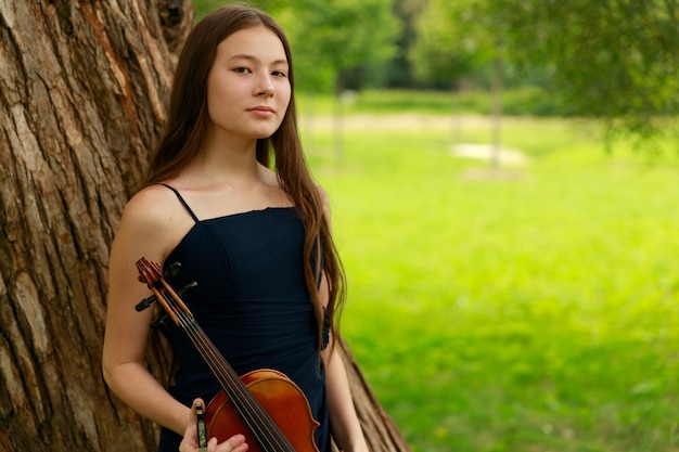 Una hermosa niña con violinistas largos se encuentra en el parque en verano. Foto de alta calidad