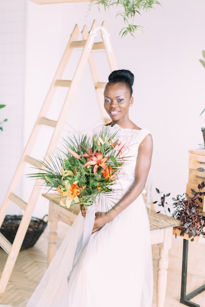 Hermosa novia afroamericana con ramo tropical en estudio