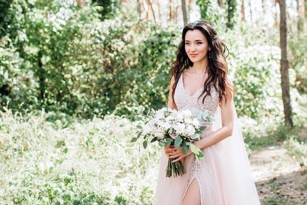 Una hermosa novia en un delicado vestido rosa al aire libre, retrato mujer morena con cabello largo oscuro