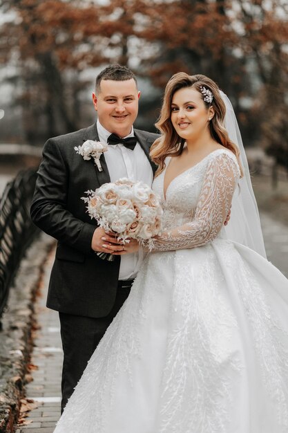 Foto una hermosa novia y un elegante novio se abrazan tiernamente y disfrutan del día una elegante pareja de recién casados concepto de matrimonio