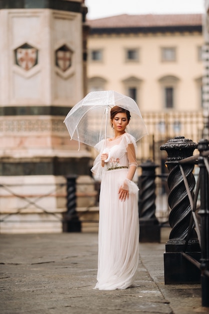 hermosa novia elegante con un paraguas camina por la ciudad vieja de Florencia.