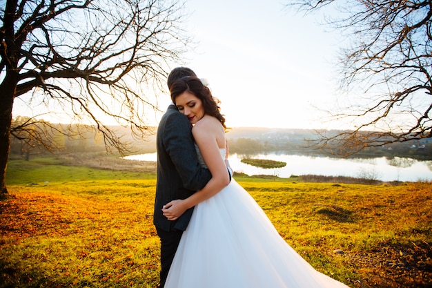 Hermosa novia con estilo feliz con novio elegante en la naturaleza